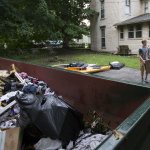 people hauling junk out to a dumpster